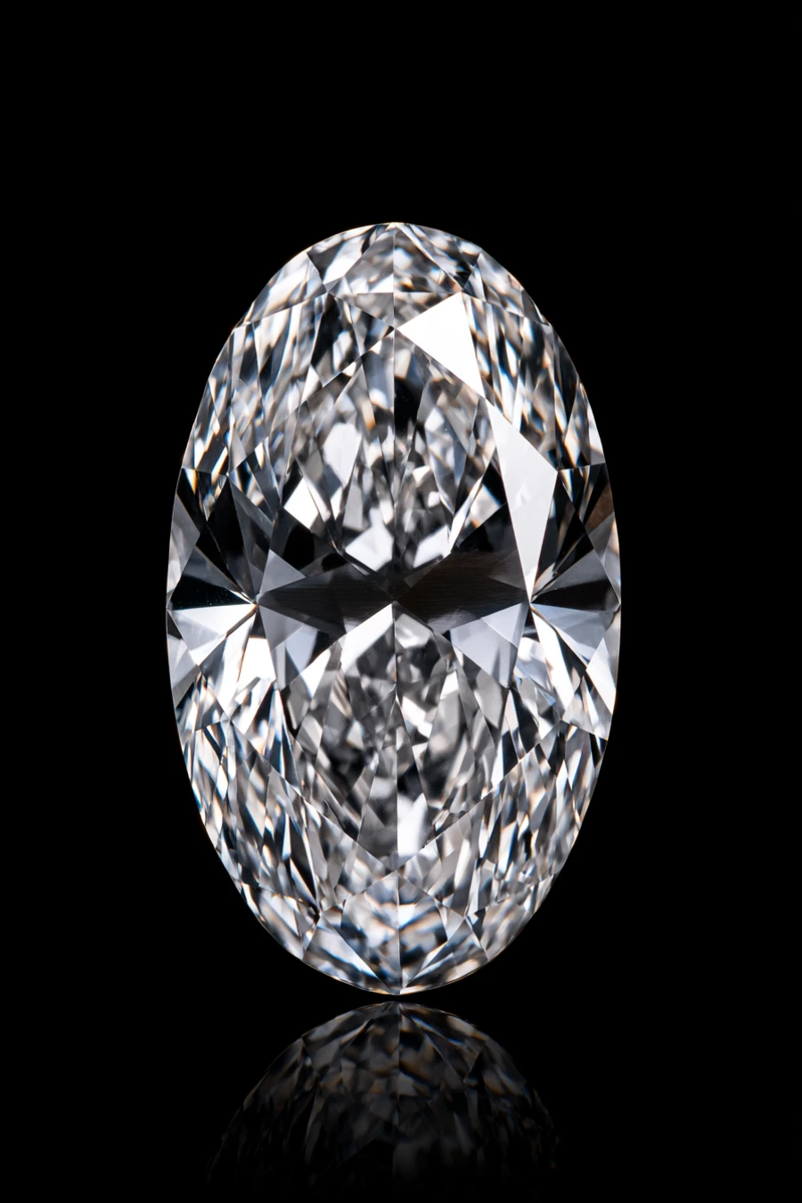Oval-cut diamond with a elongated silhouette and brilliant symmetrical facets shown upright against a glossy black background