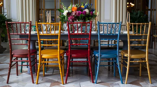 a group of colorful chairs and a vase of flowers on a table