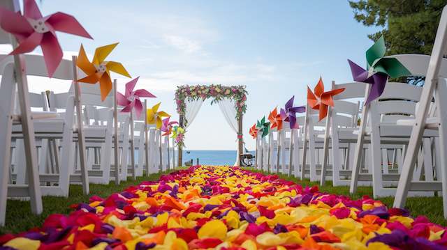 a wedding aisle with white chairs and colorful petals Paper Pinwheels