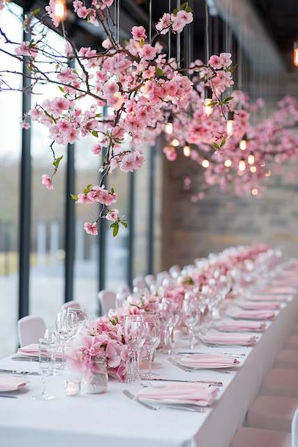 blooming cherry blossom branches suspended over a wedding dinner table