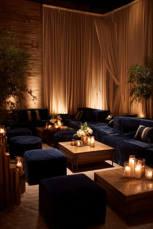 Elegant wedding cocktail lounge with navy velvet seating, wooden tables, and soft candlelight Elegant wedding cocktail lounge with navy velvet seating, wooden tables, and soft candlelight
