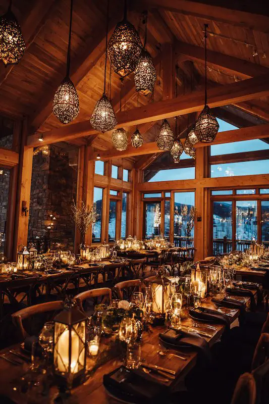 Rustic winter wedding dinner setting with candlelight, wood beams, and elegant pendant lights overhead Rustic winter wedding dinner setting with candlelight, wood beams, and elegant pendant lights overhead
