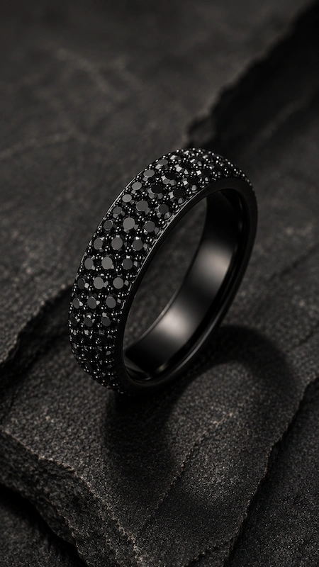 Black pavé diamond men’s wedding band on dark stone surface in a dramatic moody luxury editorial close-up scene