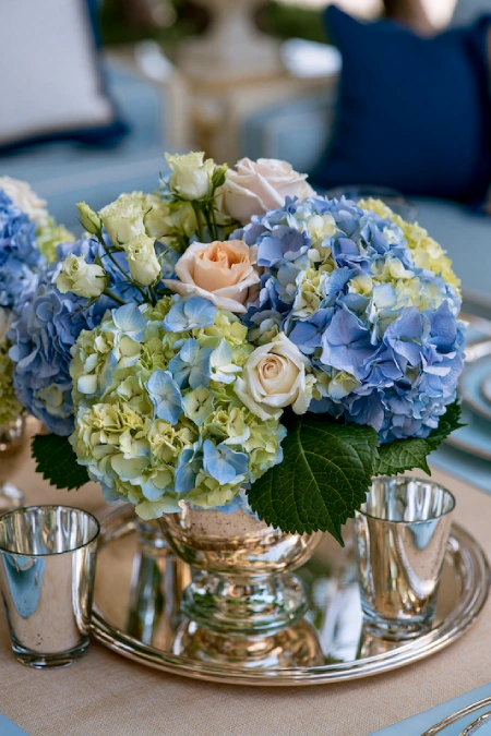 Blue hydrangea centerpiece with blush roses and silver accents for an elegant rehearsal dinner table setting