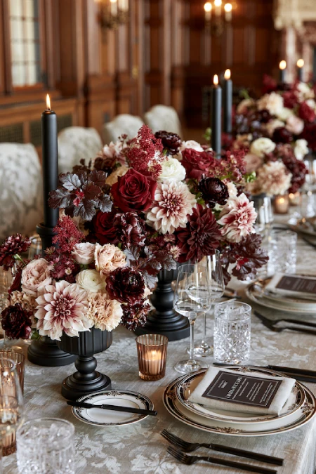 25 Fall Wedding Centerpieces With Main Character Energy (Cozy, Never Costume-y) 8 Moody burgundy and blush floral centerpieces with black candlesticks on an elegant fall wedding reception table