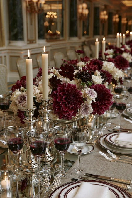 25 Fall Wedding Centerpieces With Main Character Energy (Cozy, Never Costume-y) 6 Burgundy dahlia wedding centerpiece with silver candlesticks, ivory blooms, and candlelight on an elegant reception table