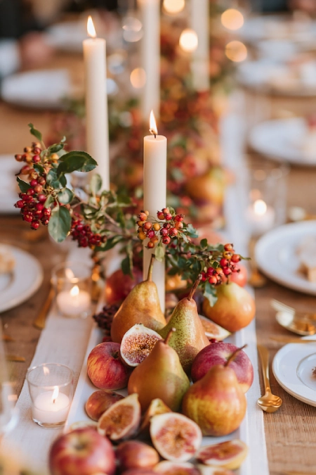 25 Fall Wedding Centerpieces With Main Character Energy (Cozy, Never Costume-y) 13 Fall wedding centerpiece with pears, figs, berries, taper candles, and seasonal fruit styled on a rustic reception table