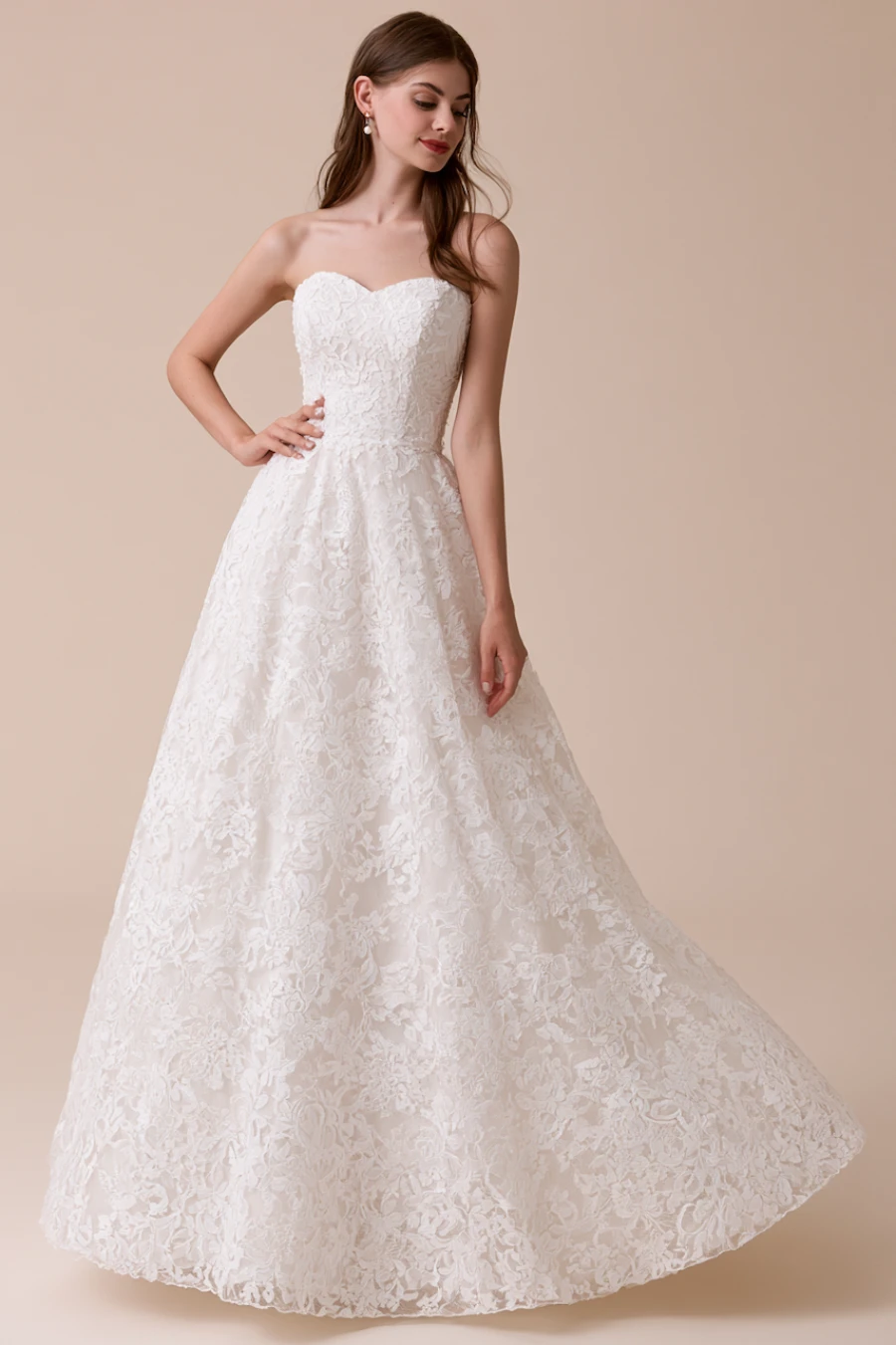 Bride wearing a lace A-line wedding dress with a sweetheart neckline and floral lace skirt in a clean studio bridal portrait
