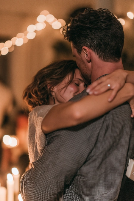 Proposal Ideas: 40 Ways to Pop the Question She'll Never Stop Talking About 2 Newly engaged couple embracing during a romantic evening dance with candlelight, string lights, and engagement ring visible