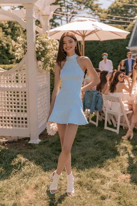 The Perfect Rehearsal Dinner Dress for Guests: Your Complete Outfit Guide 10 Woman in a pale blue mini dress at an outdoor garden rehearsal dinner with a playful and modern summer look