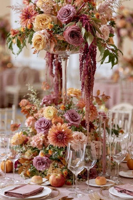 25 Fall Wedding Centerpieces With Main Character Energy (Cozy, Never Costume-y) 23 Tall floral wedding centerpiece with mauve roses, peach dahlias, cascading amaranthus, and lush blooms on a luxury reception table