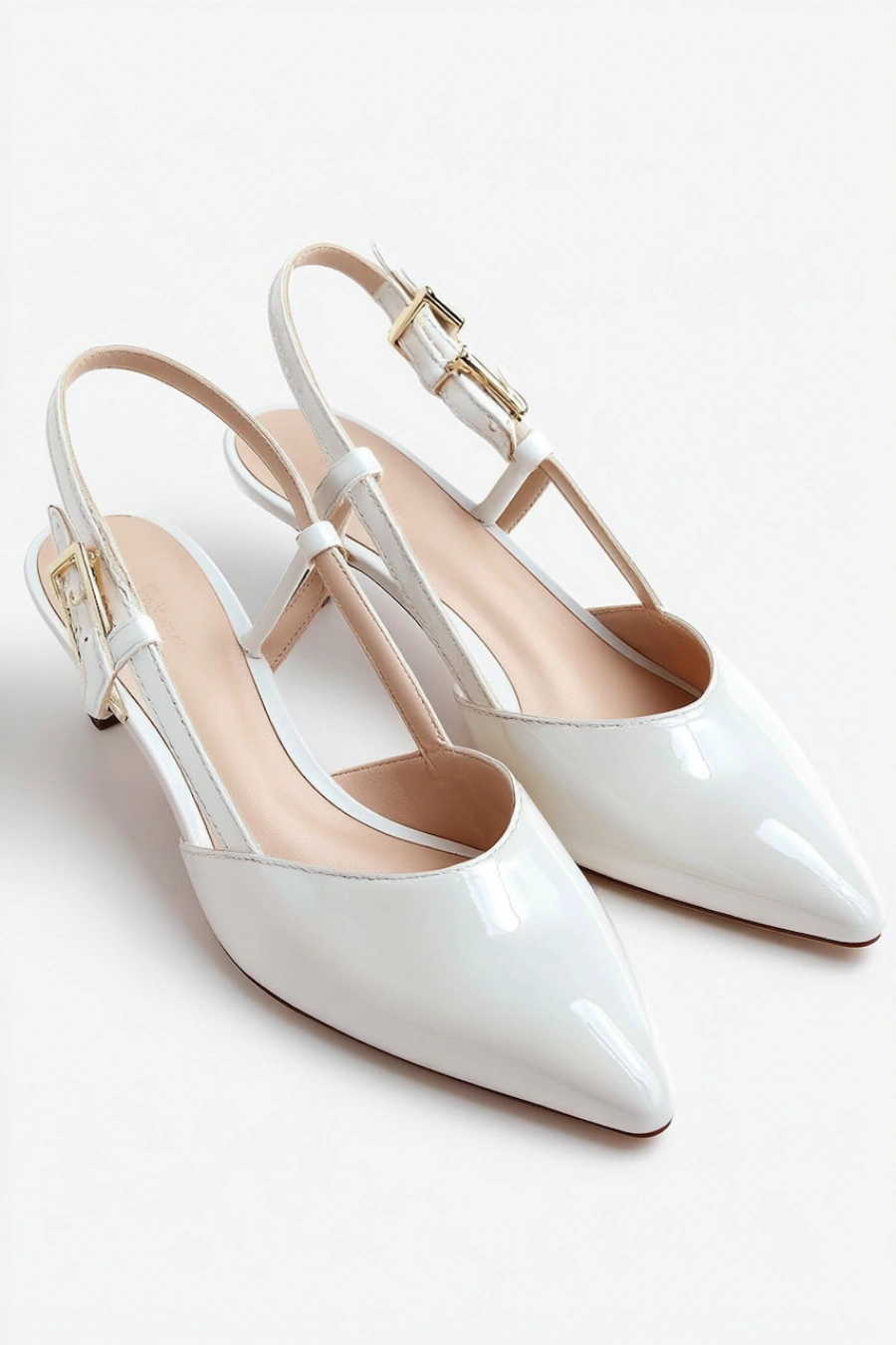Wedding Shoes for the Bride: 27 Beautiful Ideas That Balance Style and Comfort 8 White patent leather slingback bridal flats with pointed toes, T straps, and gold buckles on a clean white studio background